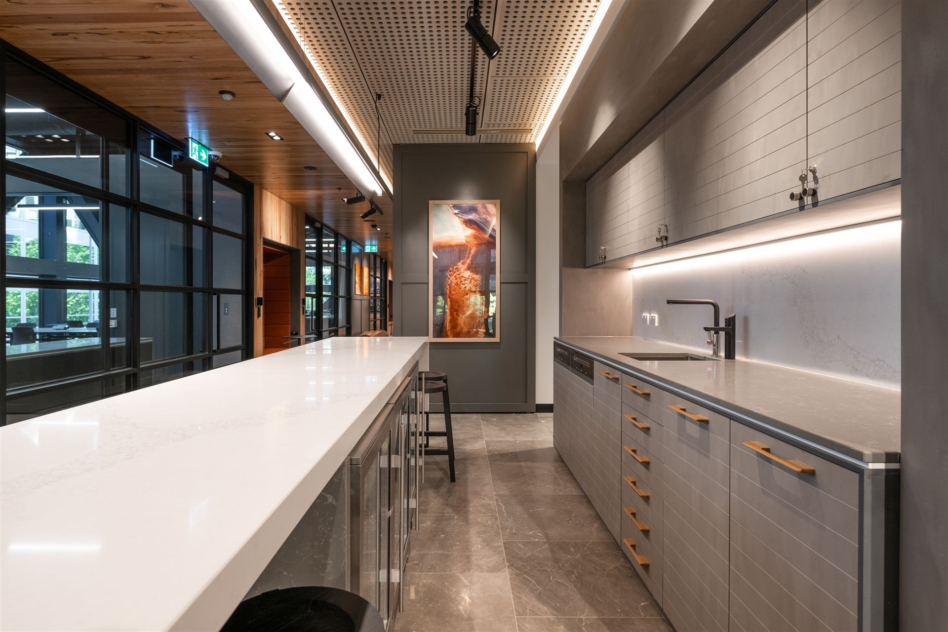 Level 5 shared kitchen — stone bar under a perforated timber ceiling