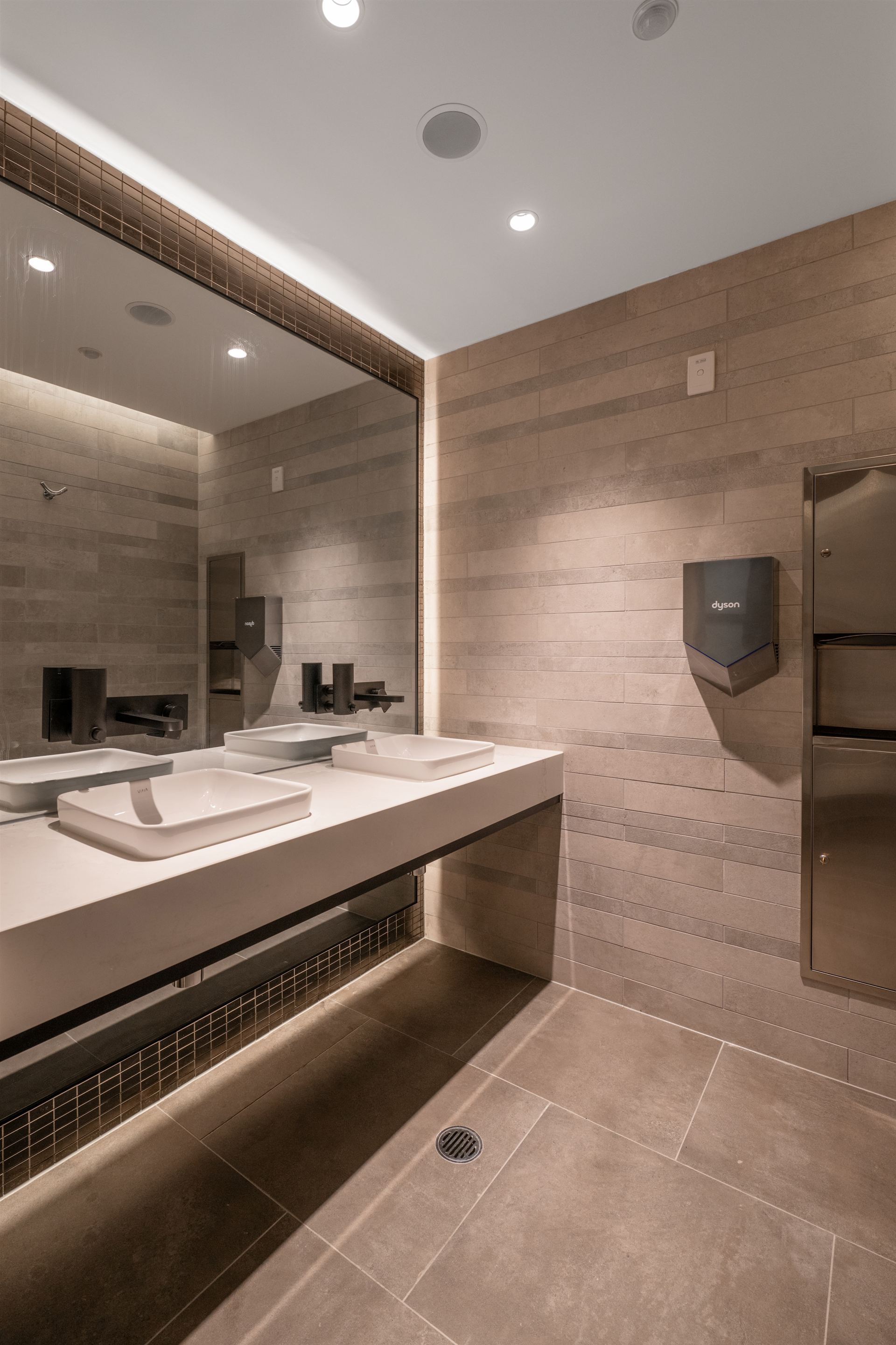 End-of-trip amenities with stone tiling and backlit mirror