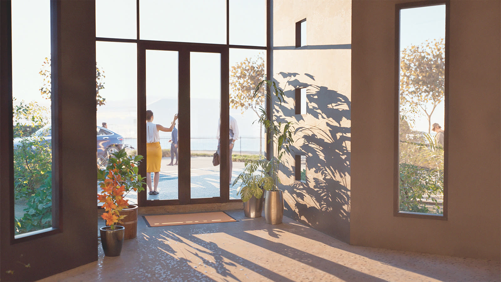 The office foyer looking out through full-height glazing, late sun across the floor