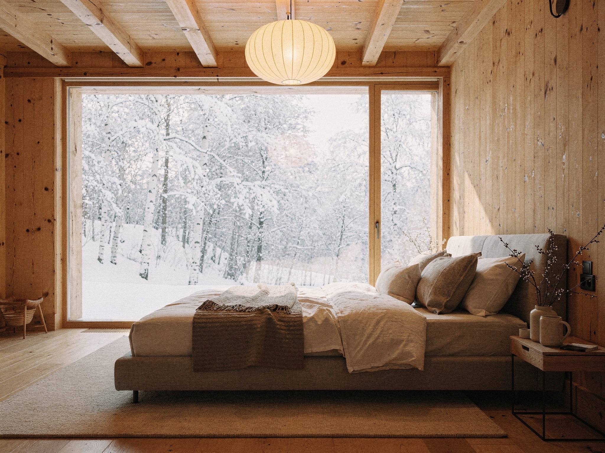 Suite bedroom facing a picture window of snowy birches in morning light