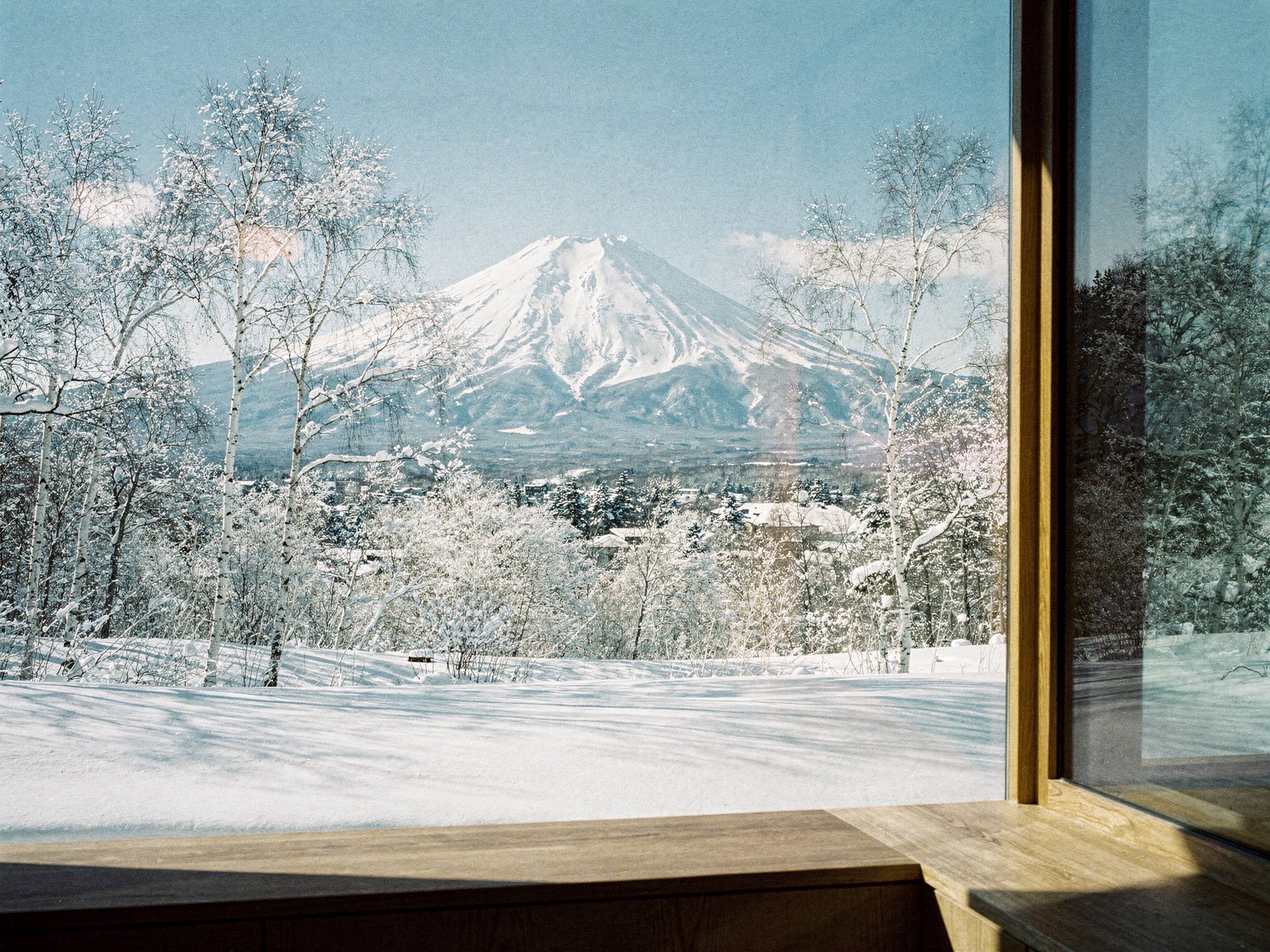 Mt Yōtei framed through full-height lodge glazing