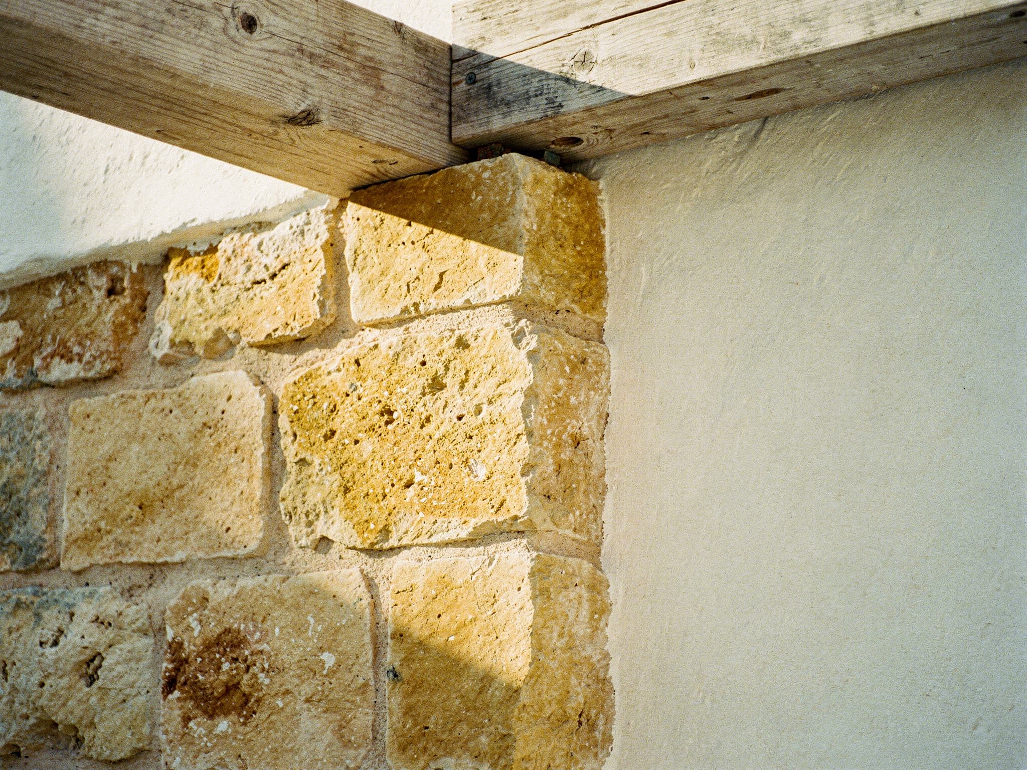 Detail of marès sandstone meeting whitewashed plaster and a timber lintel