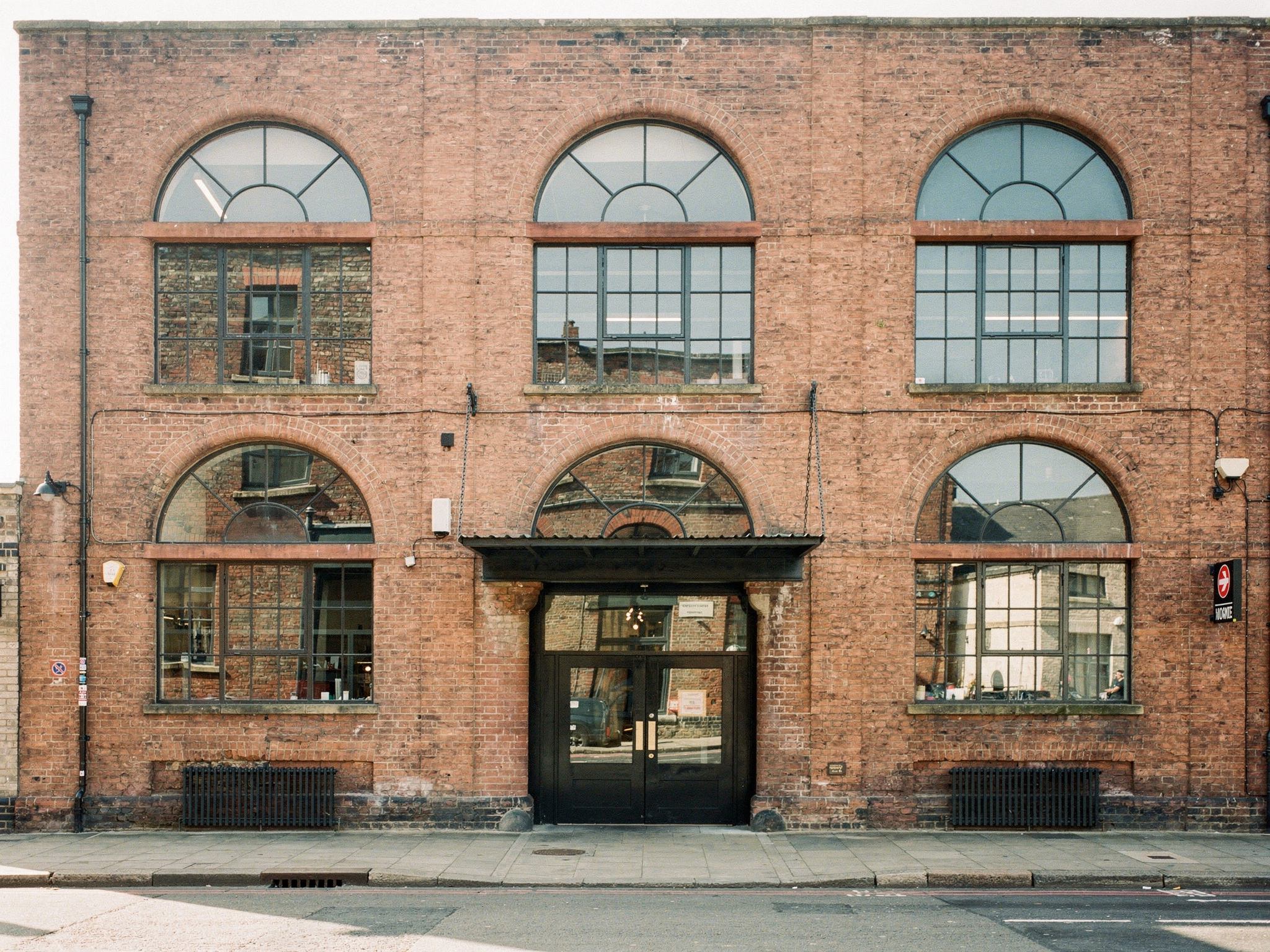 The red-brick facade with tall cast-iron arched windows, straight on