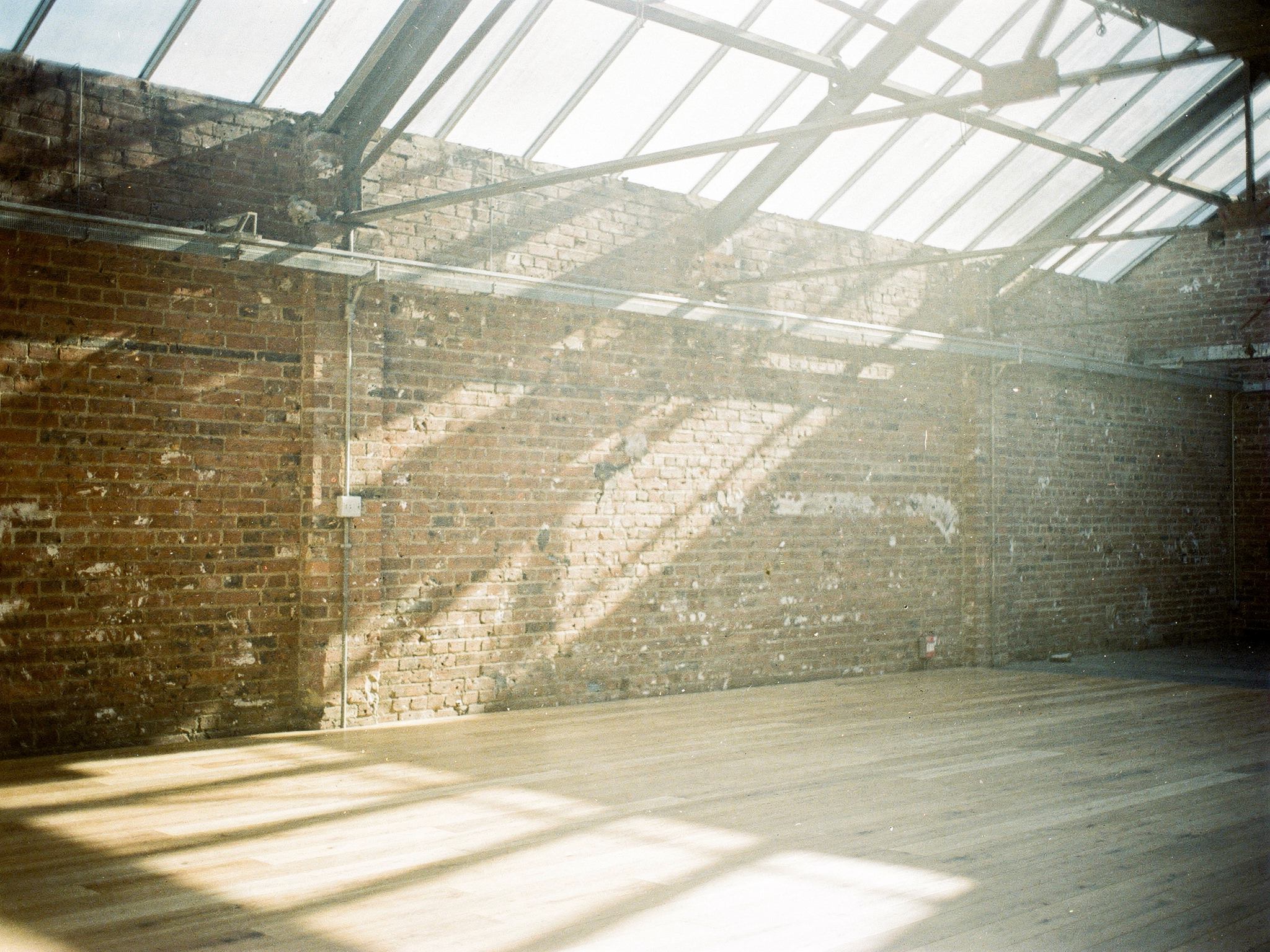 Roof-light shafts falling across an exposed brick wall and oak floor