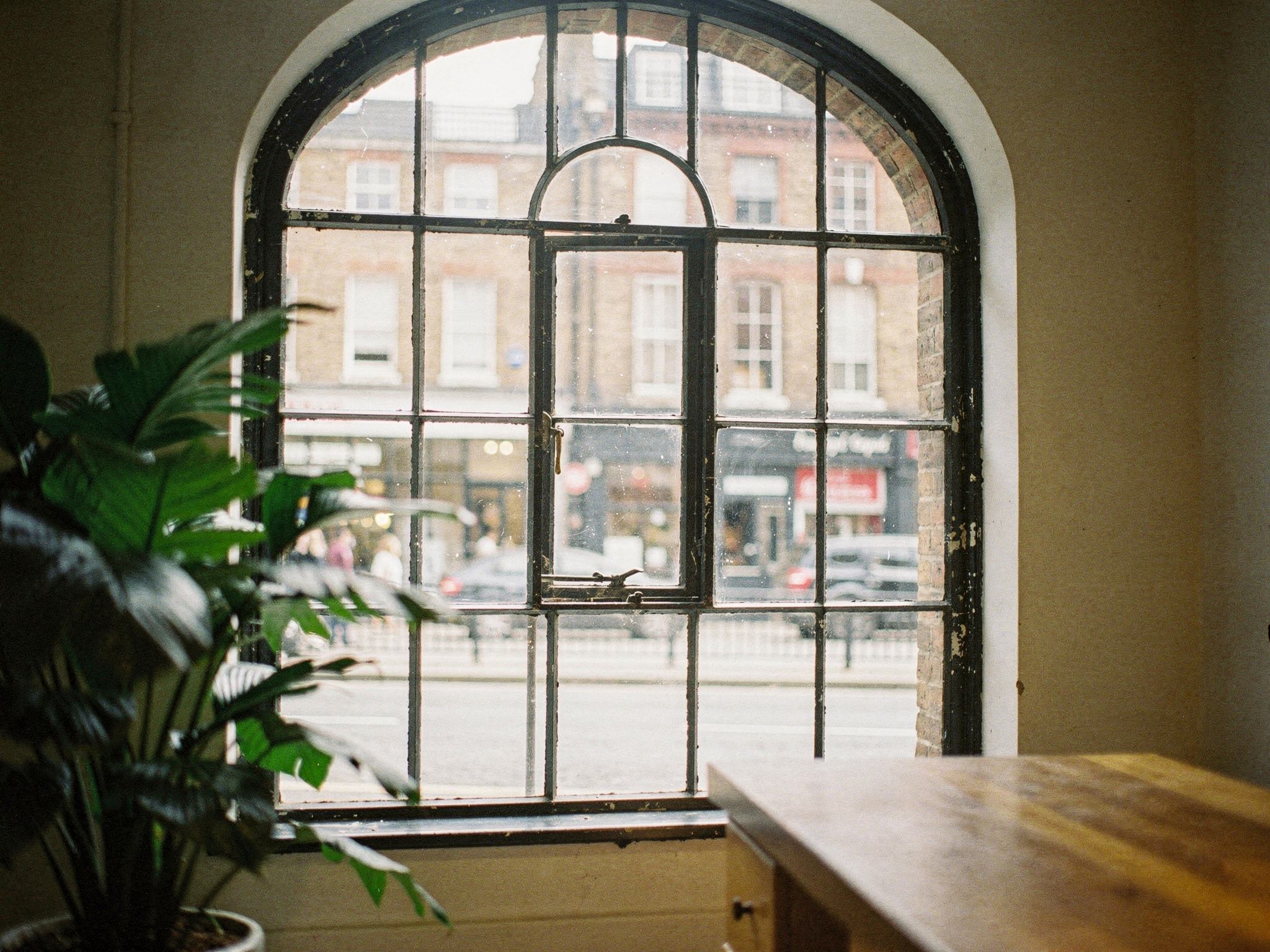 View through a tall cast-iron arched window to a bright London street