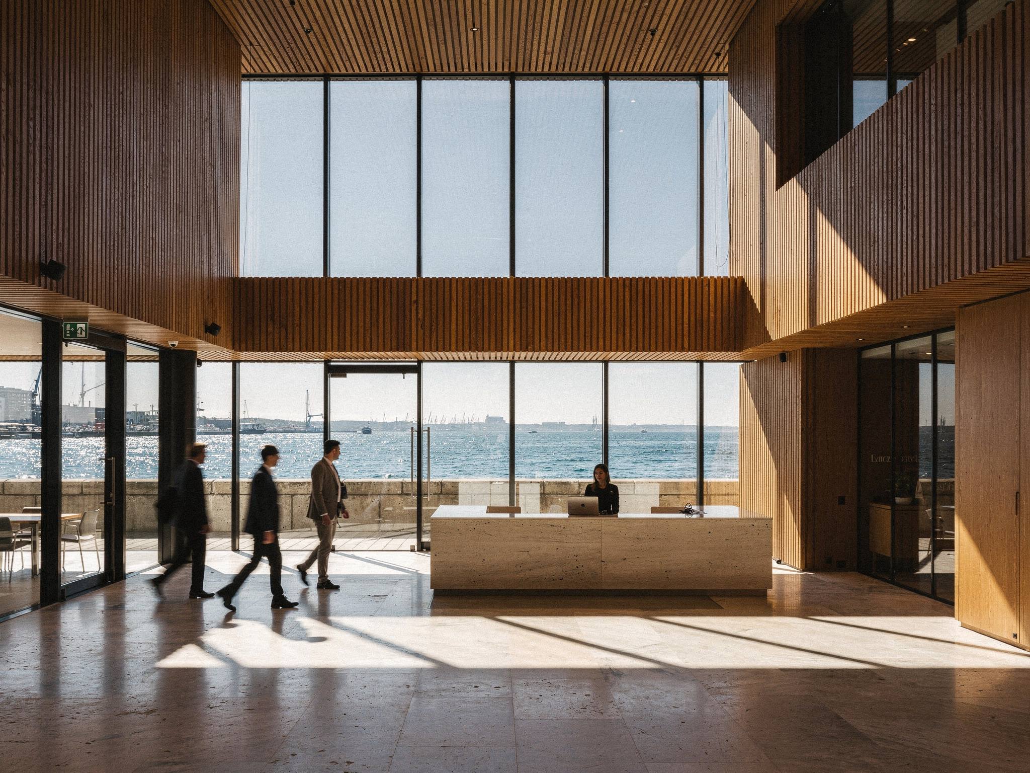 Double-height timber-lined lobby with stone floor and harbour view