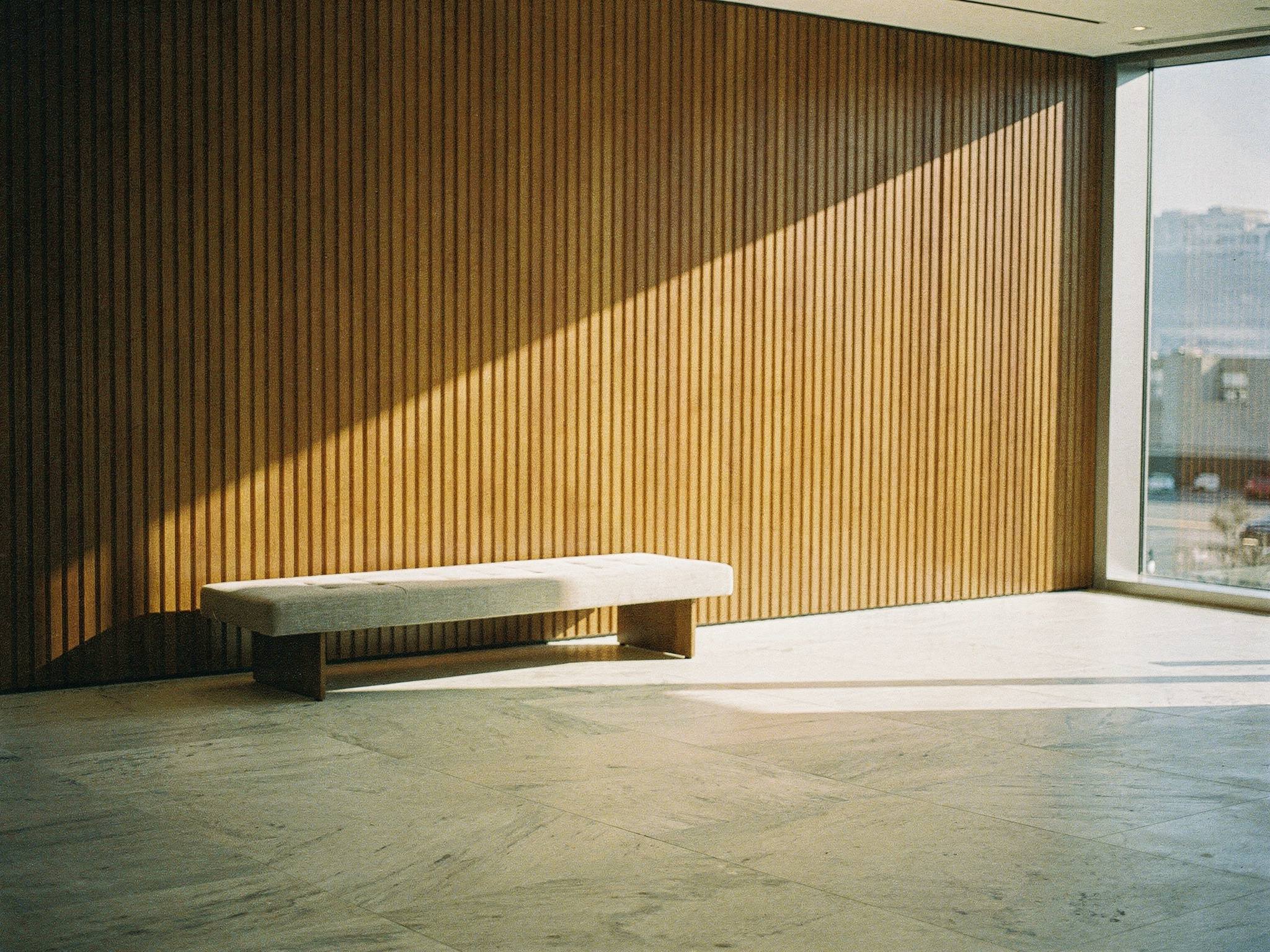 Morning light raking across a timber-battened wall and stone floor