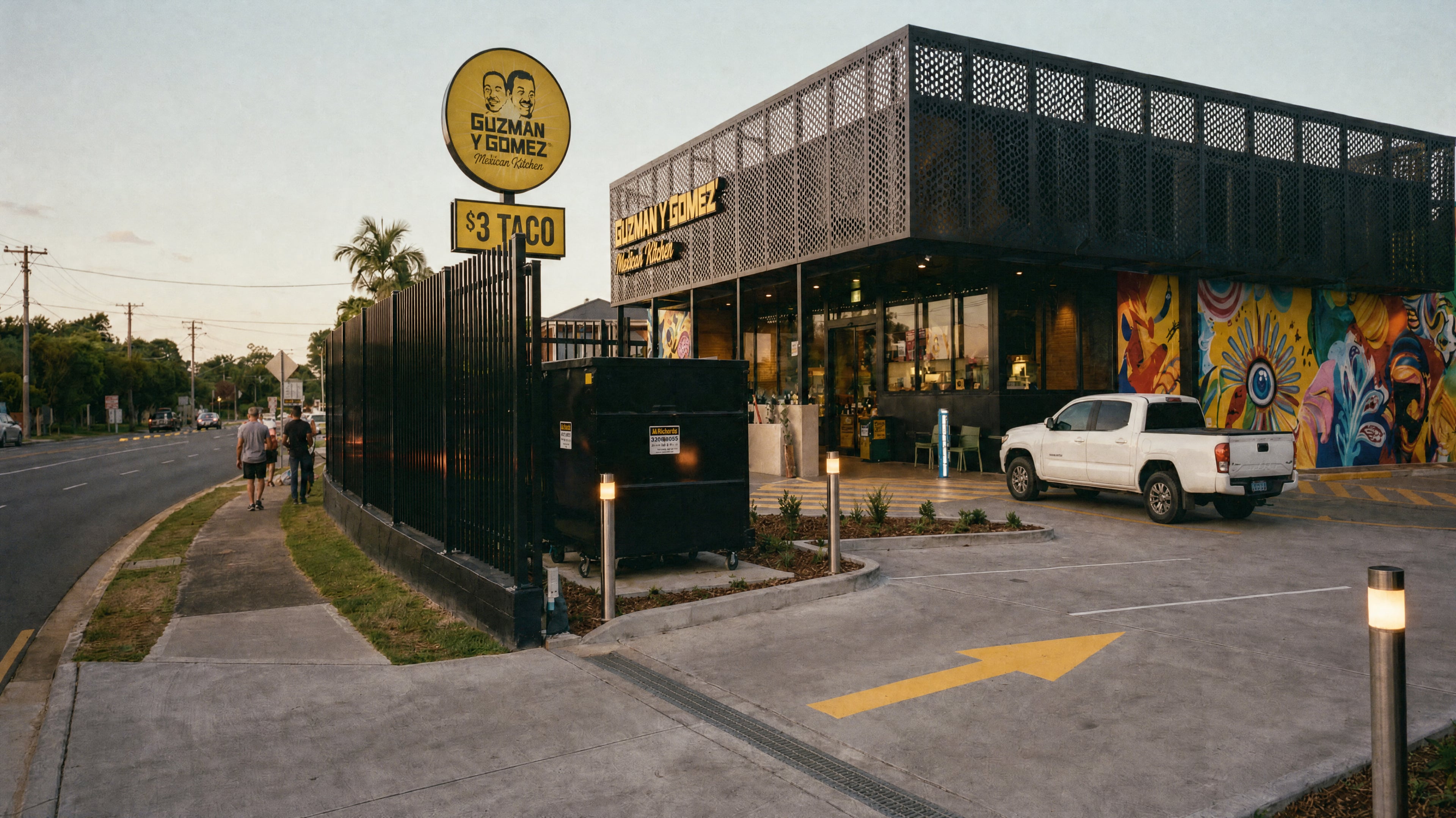 IBUY Industrial feasibility — a compact two-storey quick-service format at dusk, its perforated screen glowing above the drive-thru court