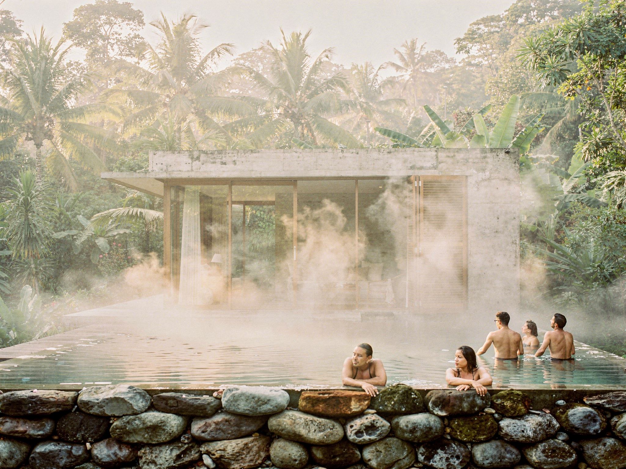 Guests in the steaming stone vitality pool in the morning mist