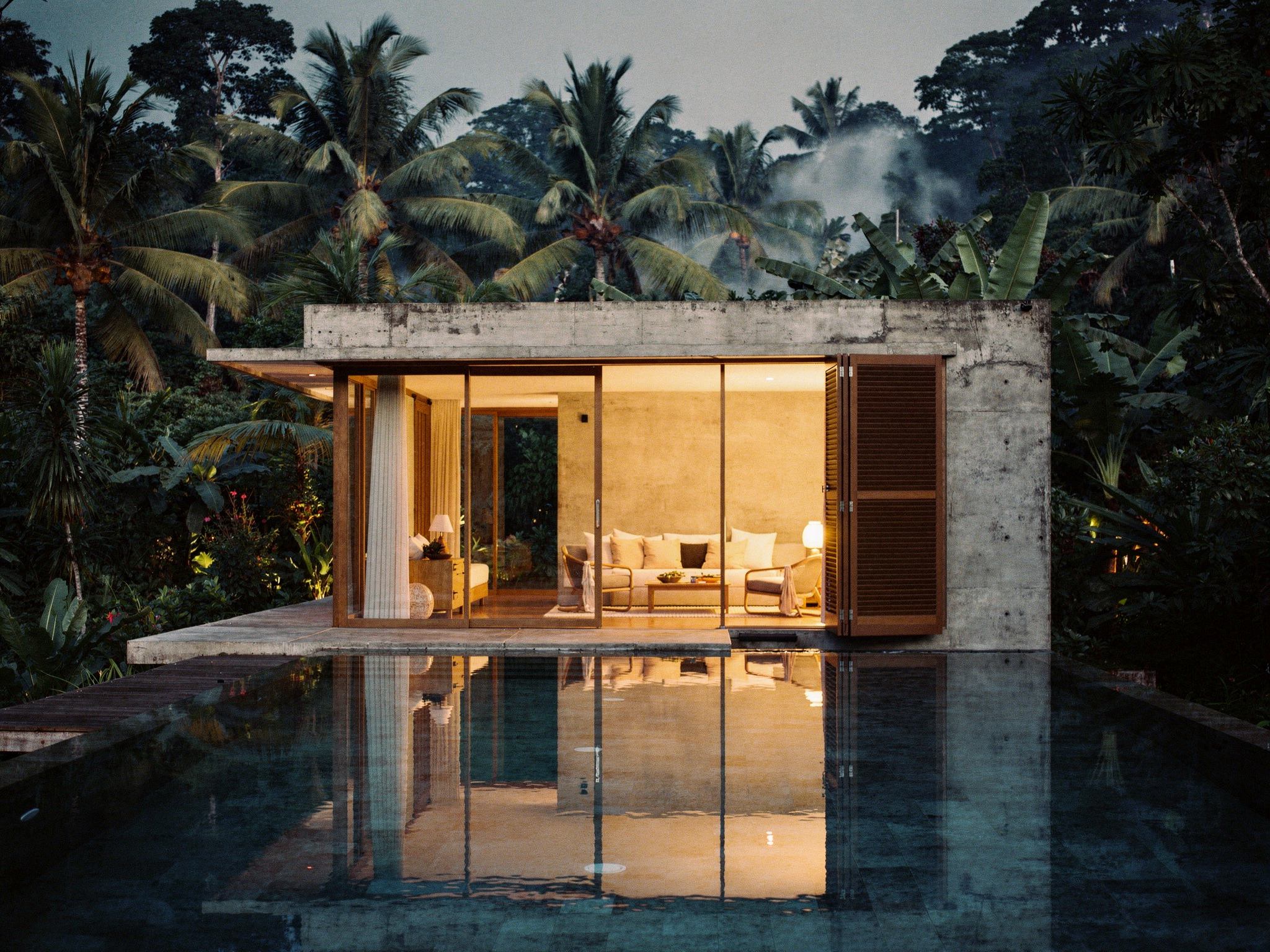 The pavilion glowing warm at dusk, reflected in the still pool