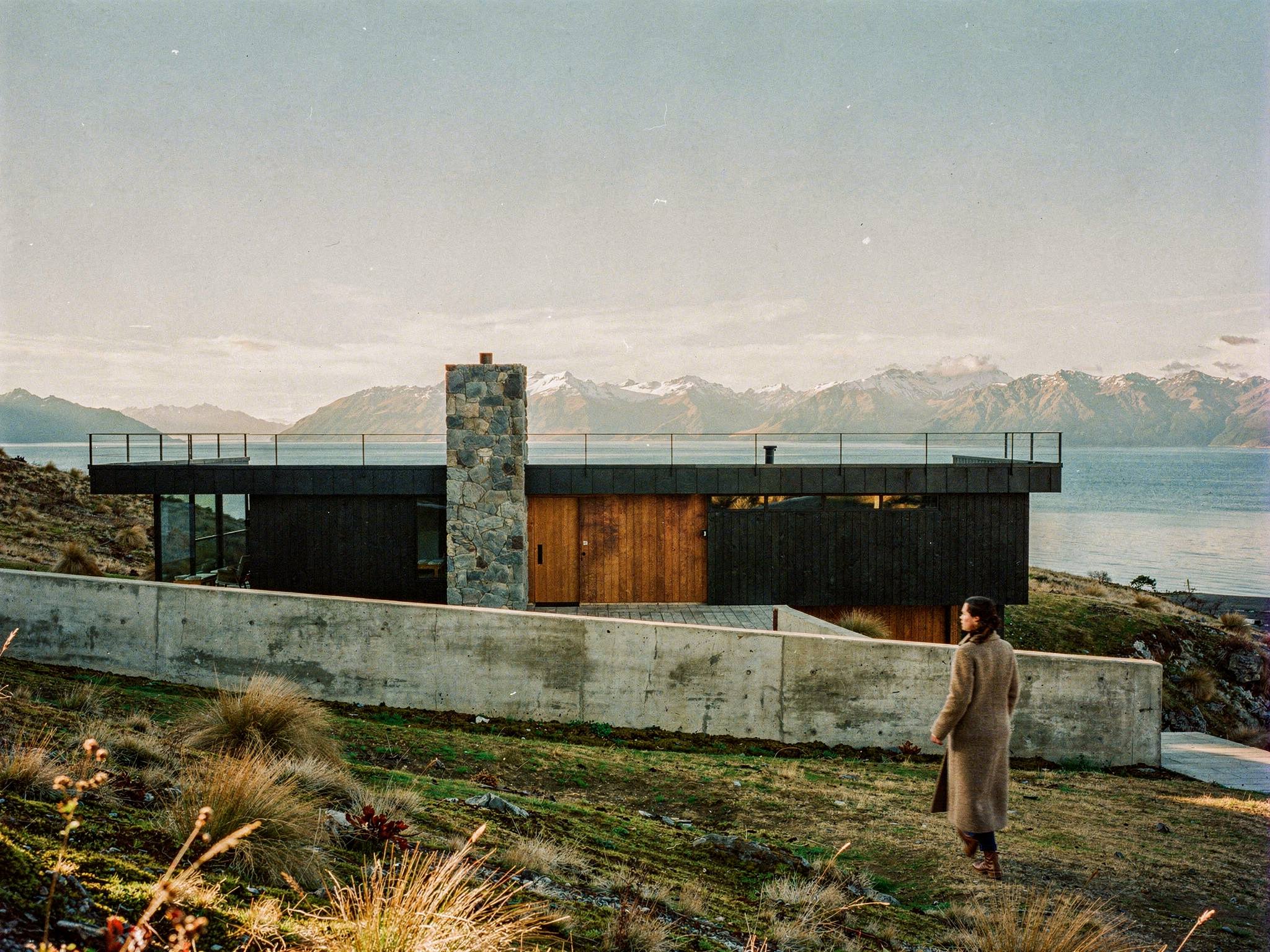 Approach along the board-formed concrete wall to the charred-timber entry