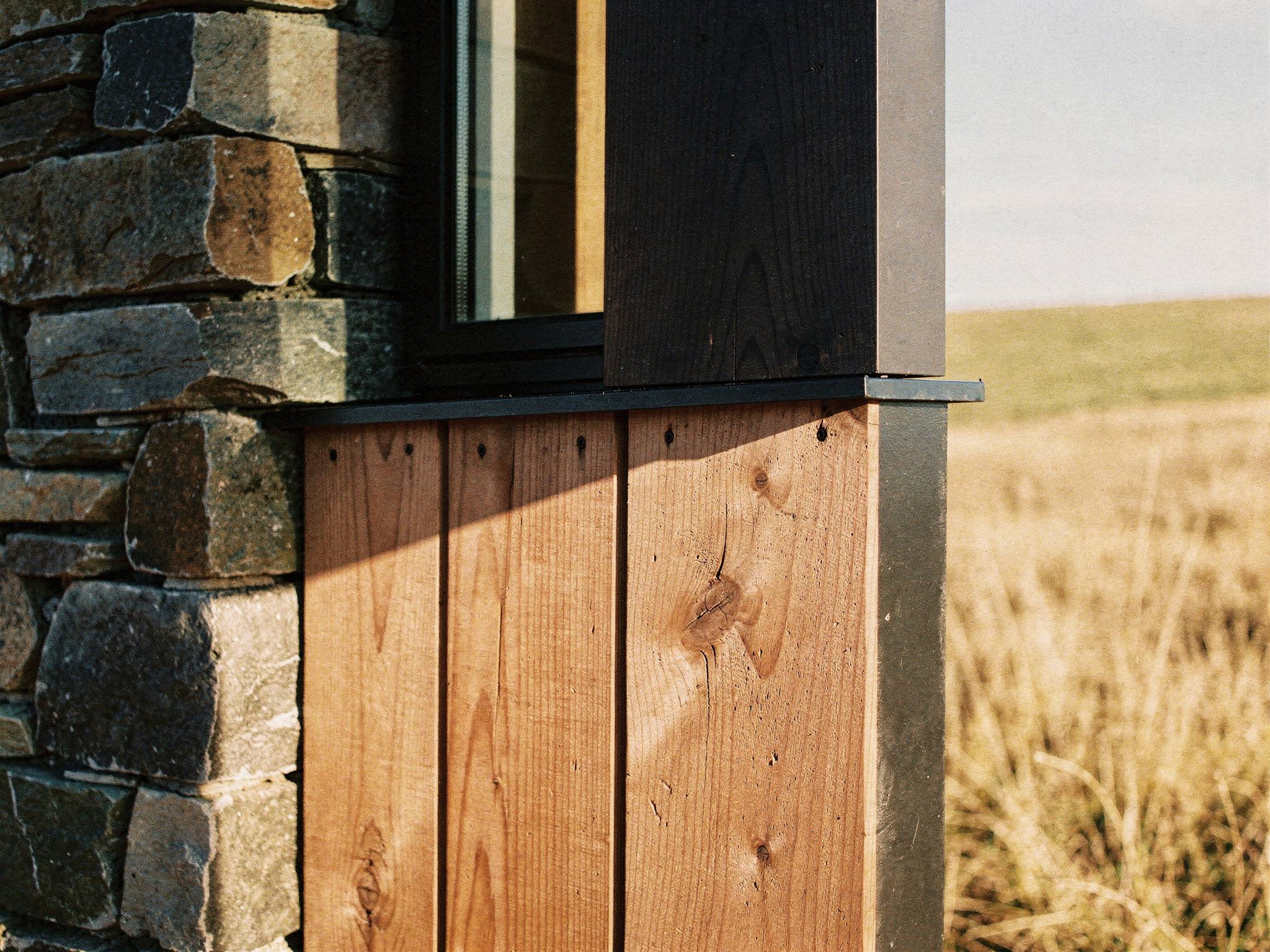 Junction detail — schist, charred board and cedar meeting the steel window sill